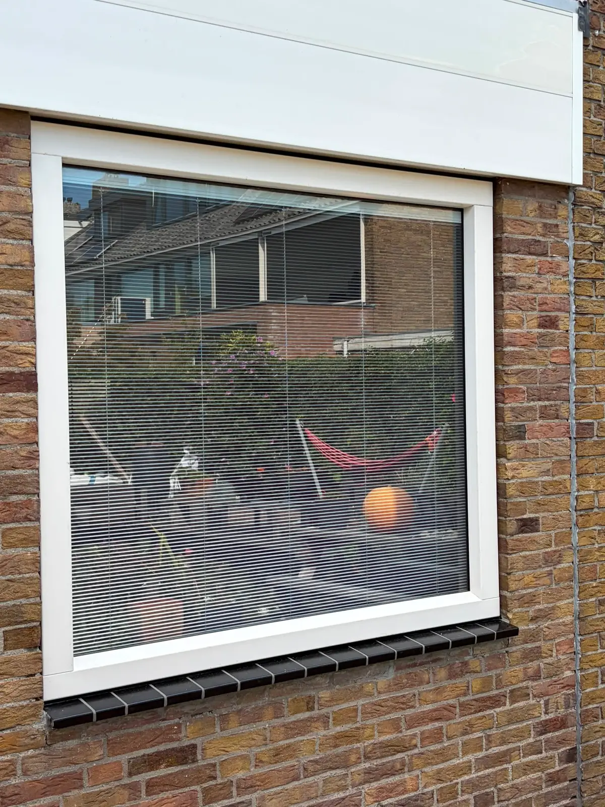 Wit kunststof raamkozijn met draaikiepraam in een bakstenen achtergevel